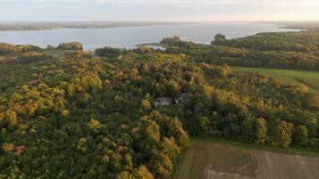 An aerial view of a forested area with a house surrounded by trees and a field.