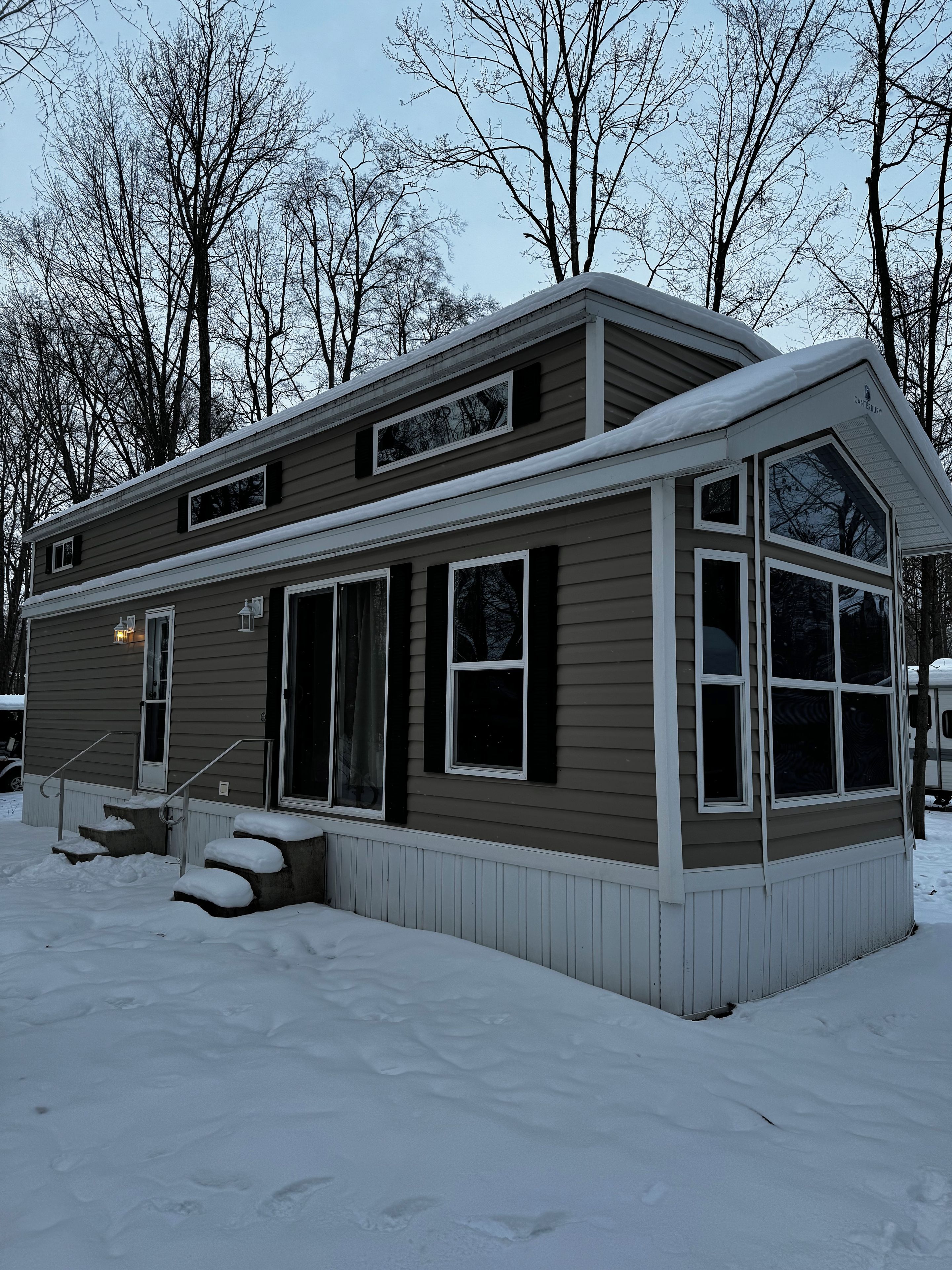 A two-story house with a covered porch and a garage, surrounded by snow.