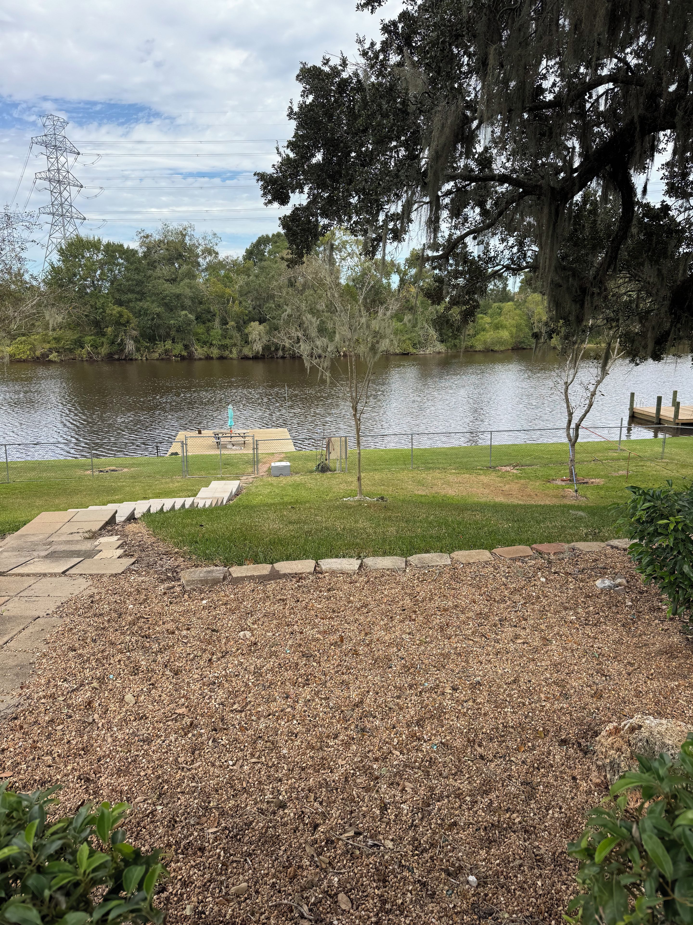 A park with a lake, a wooden dock, and a grassy area with a playground.