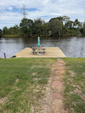 A wooden dock extending into a calm lake, with a picnic table and umbrella in the center.