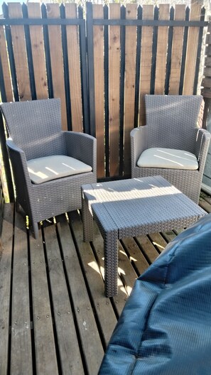 Un patio con mobiliario de mimbre, incluyendo dos sillas y una mesita.