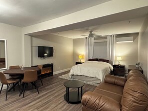 Une chambre d’hôtel comprenant un lit, un canapé, une table à manger avec des chaises, un téléviseur et un ventilateur de plafond.
