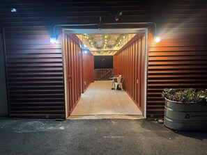 A garage entrance with a ramp leading to a door, a chair, and a planter outside. - Cozy Studio with Electric Fireplace near Jim Thorpe (Nesquehoning)