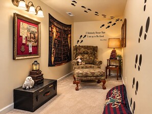 A cozy room with a bookshelf, a plush armchair, a small table with a lamp, and a wall with a Harry Potter quote. - Lakewood Manor, near Massanutten Resort (Harrisonburg)