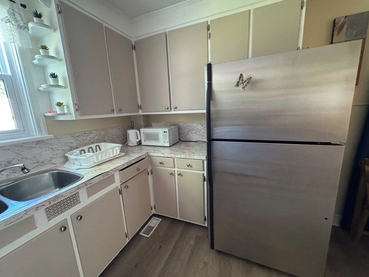 A kitchen with a stainless steel refrigerator, a microwave, a sink, and cabinets.