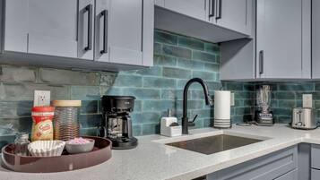 A kitchen with grey cabinets, a coffee maker, a blender, and a toaster.