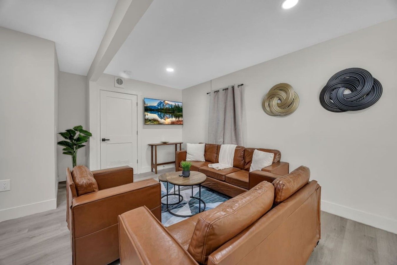 A modern living room with leather sofas, a coffee table, and a painting on the wall.