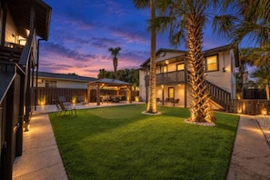 A residential property with a well-maintained lawn, a covered patio area, and a two-story house with a balcony. - Sun, Sand & Fire Pit Nights | 3 Blocks to Beach (Jacksonville Beach)