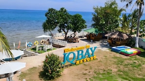 Vista desde la playa de un resort, con un cartel que dice 'Welcome to IQ BAY RESORT'.