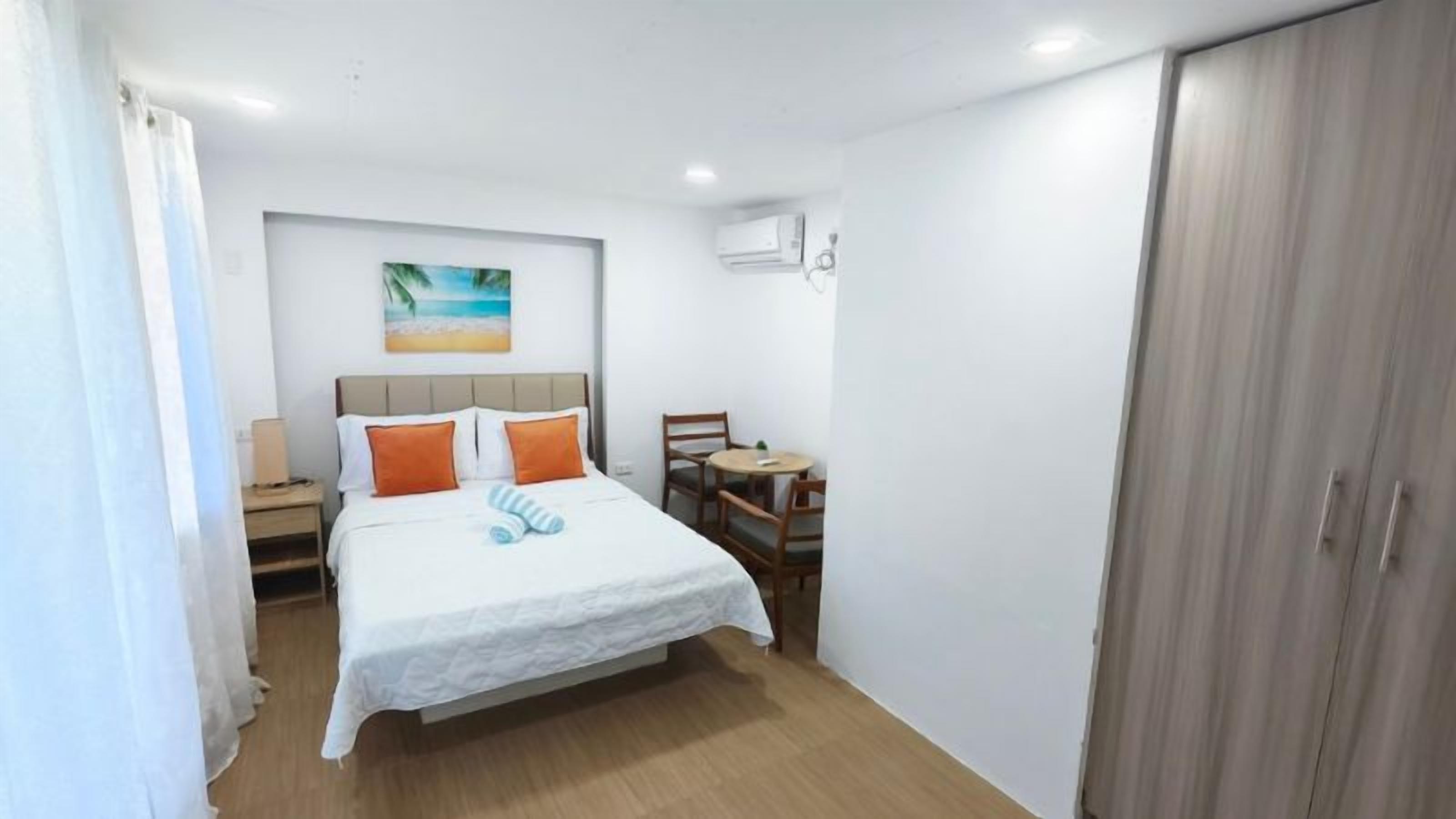 A bedroom with a bed, a desk, and a wardrobe.