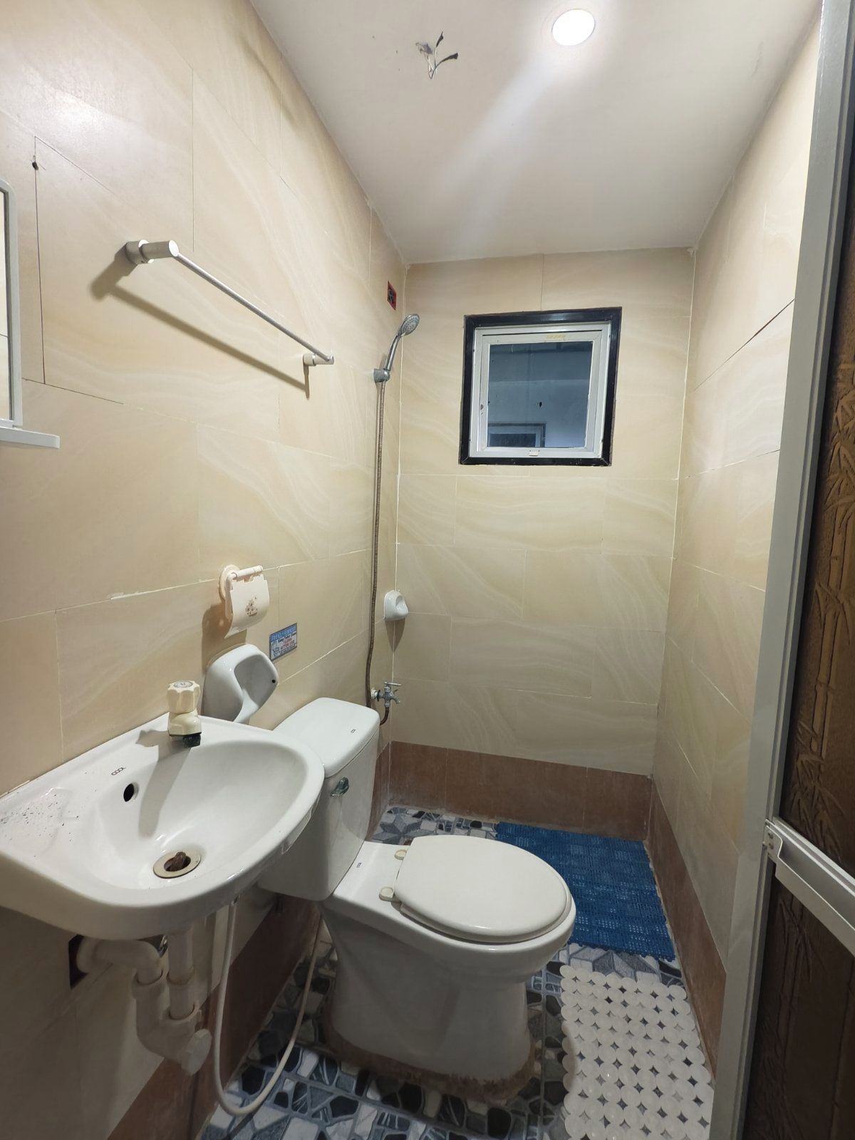 A small bathroom with a toilet, sink, and shower.