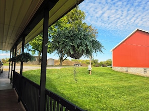 A covered porch with a view of a red barn and a grassy yard. - The Brick House /12 min drive to Hershey Park/ (Palmyra)