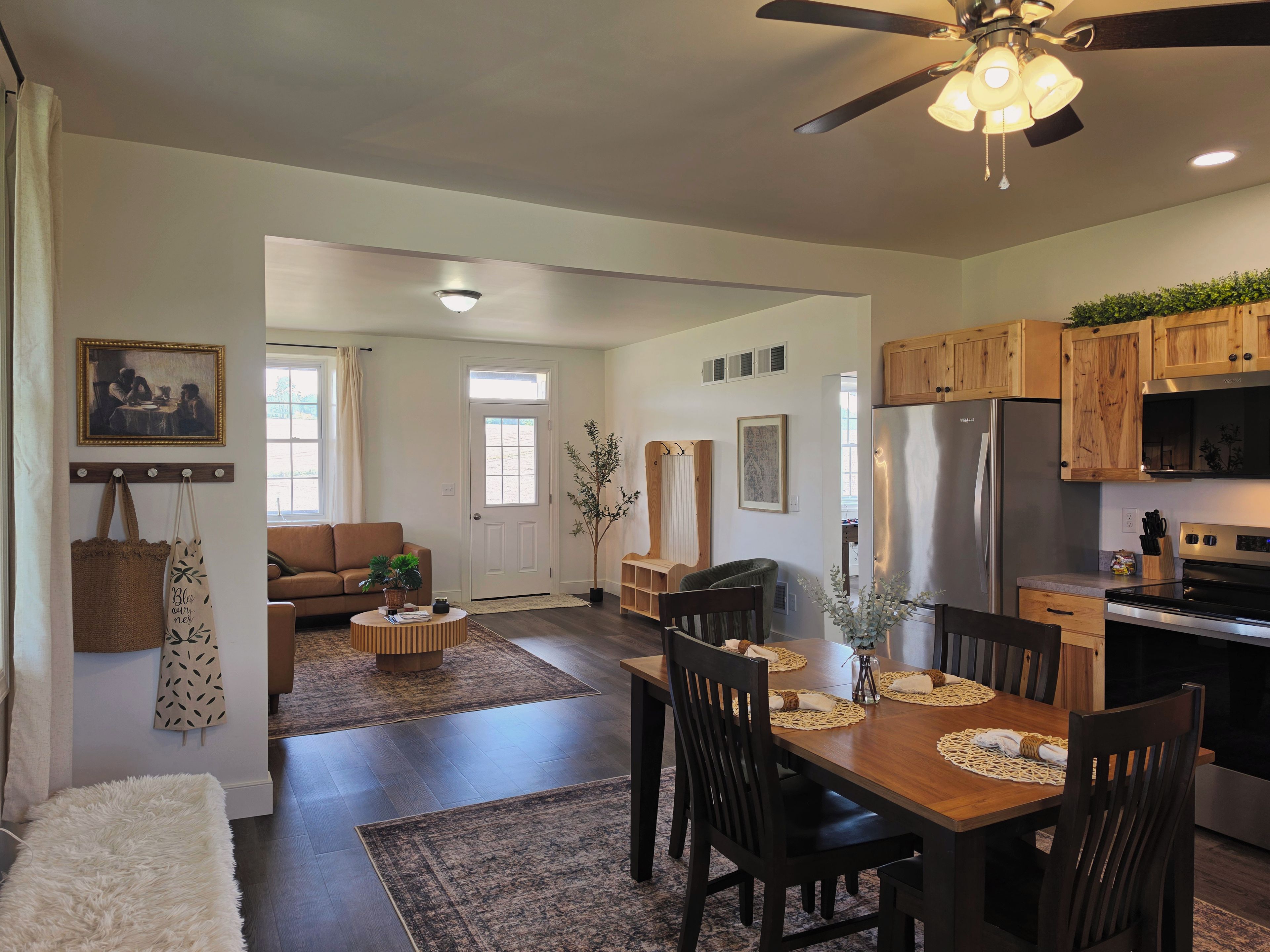 A modern kitchen with wooden cabinets, a stainless steel refrigerator, and a dining area with a wooden table and chairs.