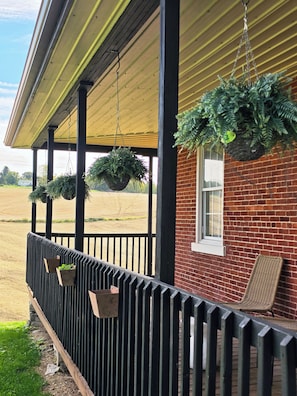 A covered porch with hanging planters and a brick wall. - The Brick House /12 min drive to Hershey Park/ (Palmyra)