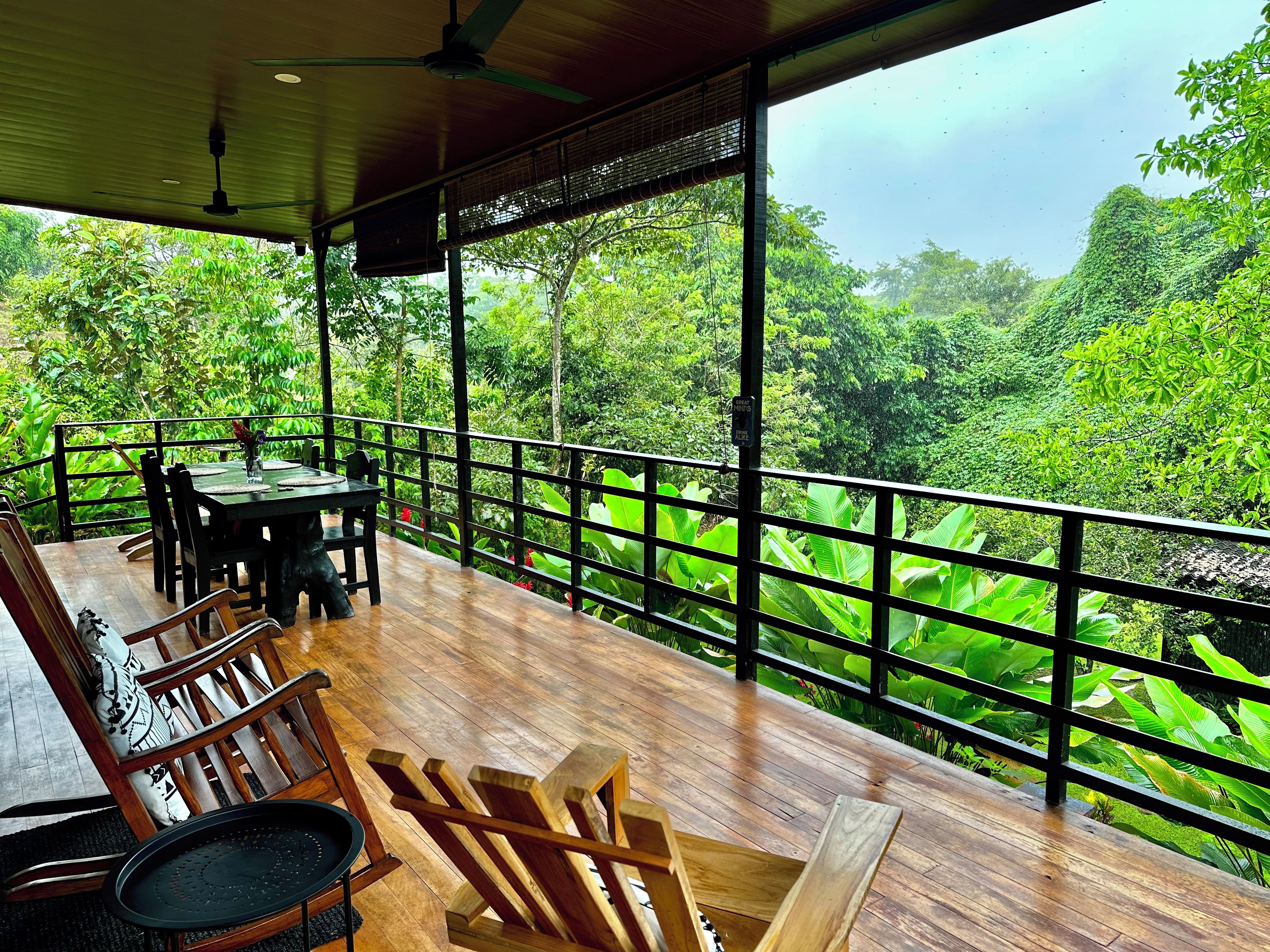 Um deck de madeira com mesa e cadeiras, com vista para uma floresta verdejante.