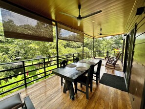 Une terrasse en bois avec une table et des chaises, donnant sur un jardin luxuriant.
