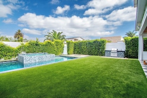 A backyard with a swimming pool, well-maintained lawn, and a barbecue grill. - Poinsettia Maison By Alora Reserve (Los Angeles)