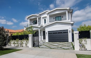 A two-story house with a garage, a driveway, and a well-maintained lawn. - Poinsettia Maison By Alora Reserve (Los Angeles)
