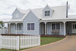 A two-story house with a porch, a picket fence, and a chimney. - Grevillea Loft House A Honey Home (Dubbo)