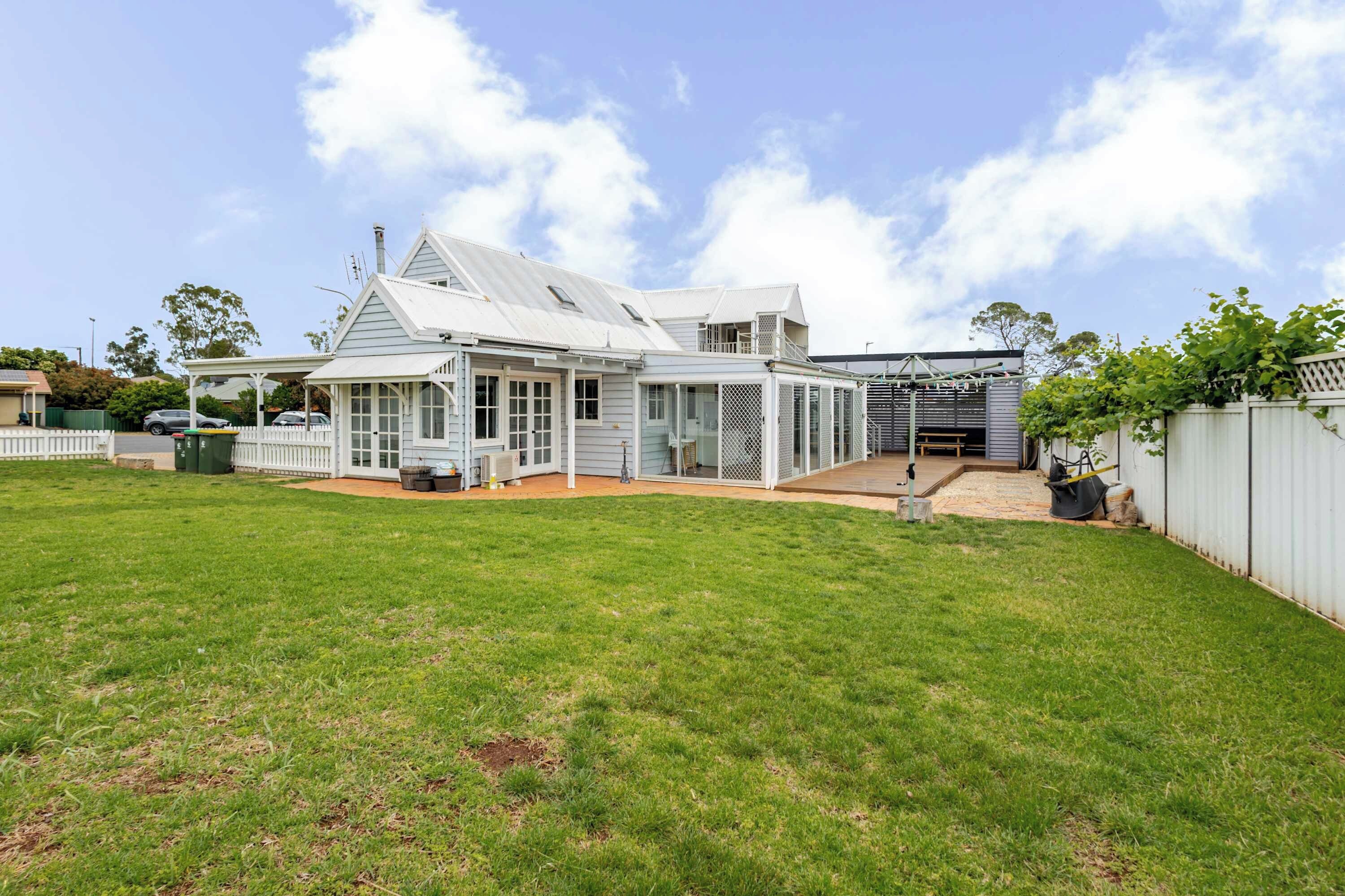 A two-story house with a covered patio and a fenced backyard.