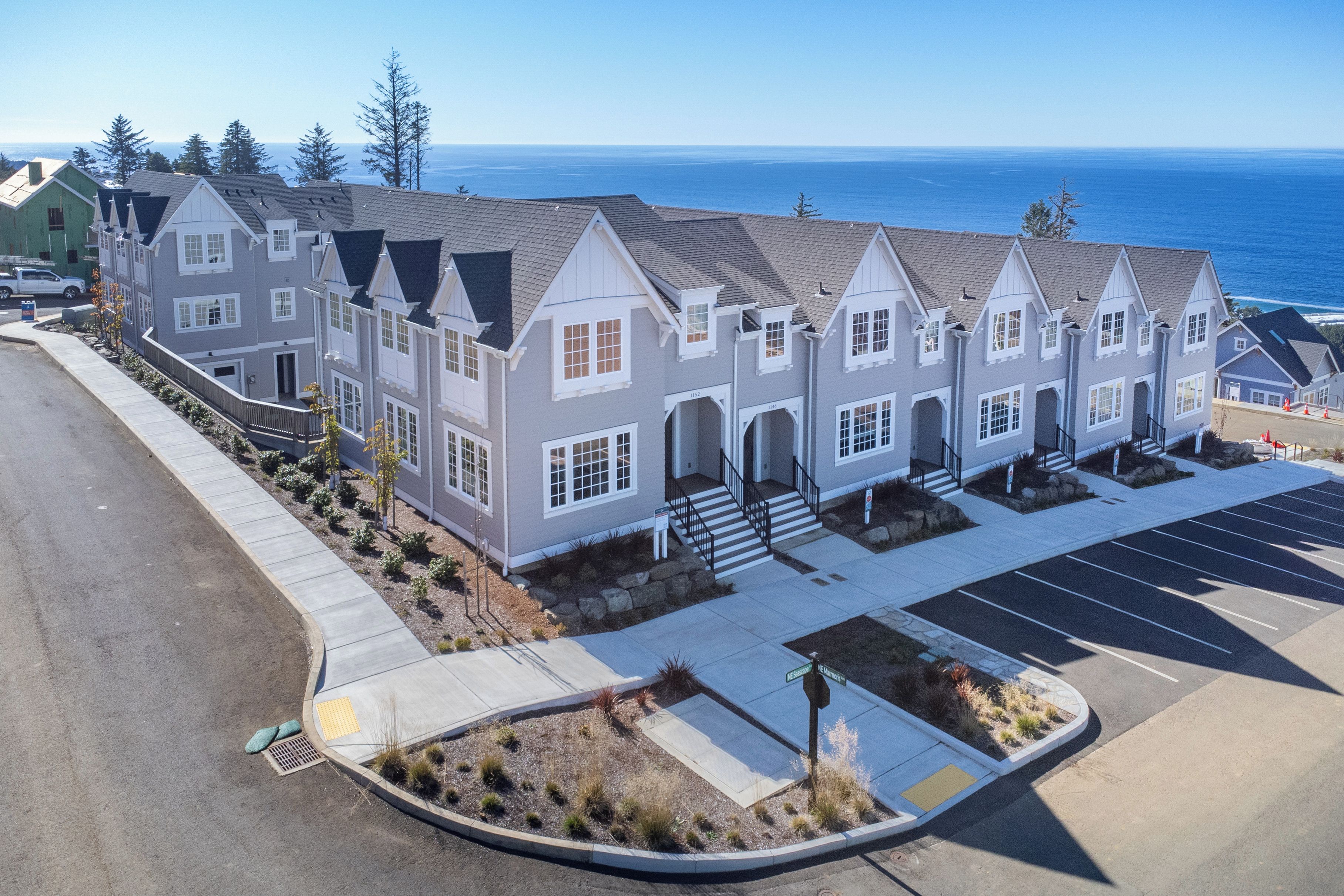 A multi-story residential building with a parking lot and a view of the ocean.