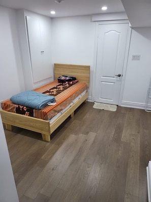 A bedroom with a wooden bed, a white door, and a white wardrobe. - Spacious 3BR/2BA · Parking + EV · Near GO Train (Brampton)