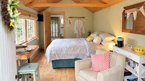 Een knus slaapkamer met een bed, een stoel, een bureau en een raam.