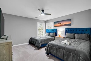 A bedroom with two beds, a ceiling fan, a painting, and a nightstand with a lamp. - Elegant living at its finest in Ashburn (Ashburn)
