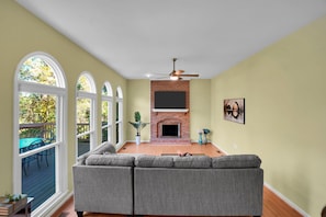 A living room with a sectional sofa, a fireplace, and a television mounted on the wall. - Elegant living at its finest in Ashburn (Ashburn)