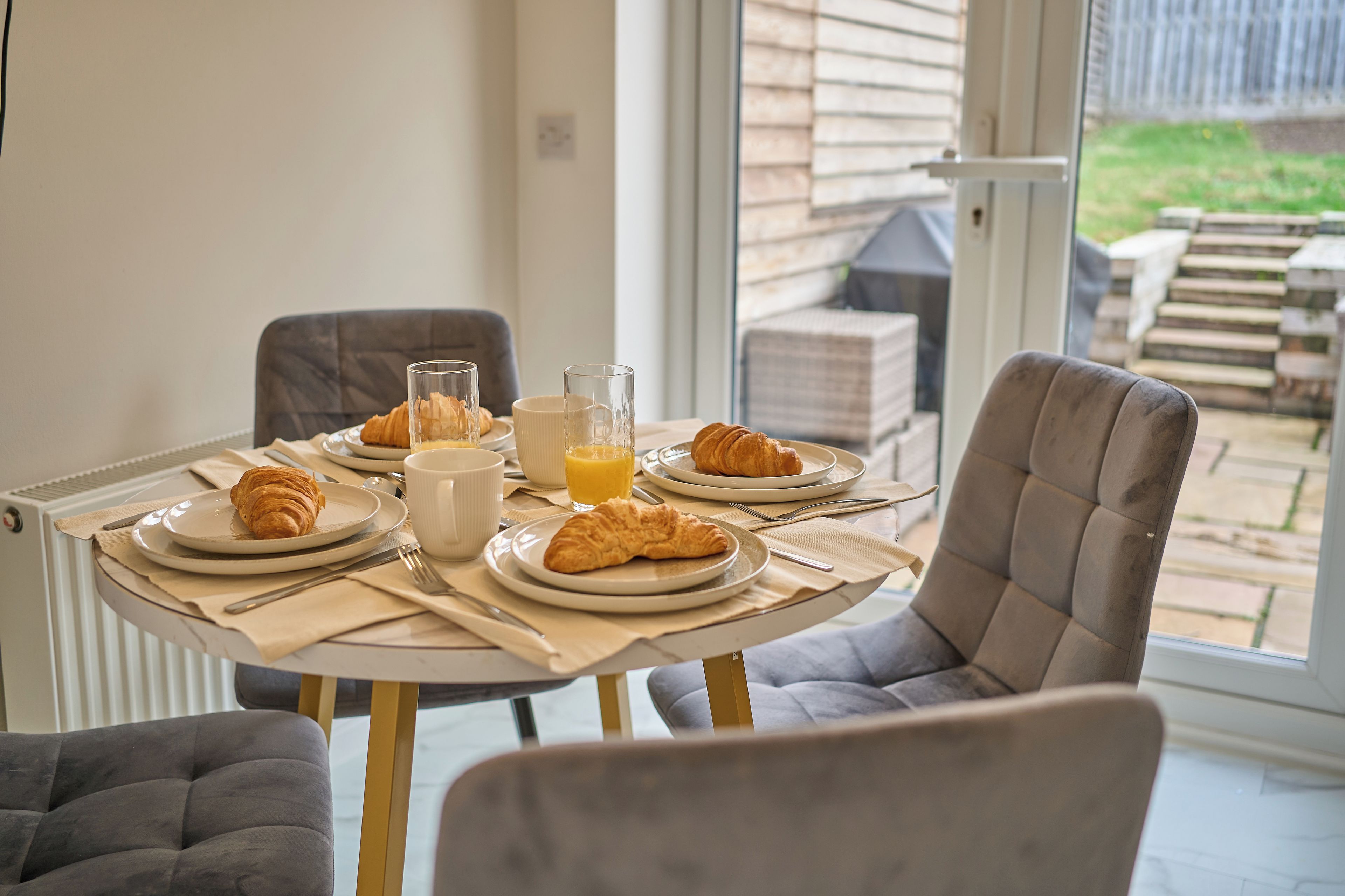 A breakfast table set with croissants, a glass of orange juice, and a white mug.