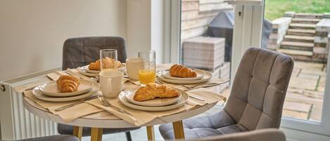 A breakfast table set with croissants, a glass of orange juice, and a white mug.