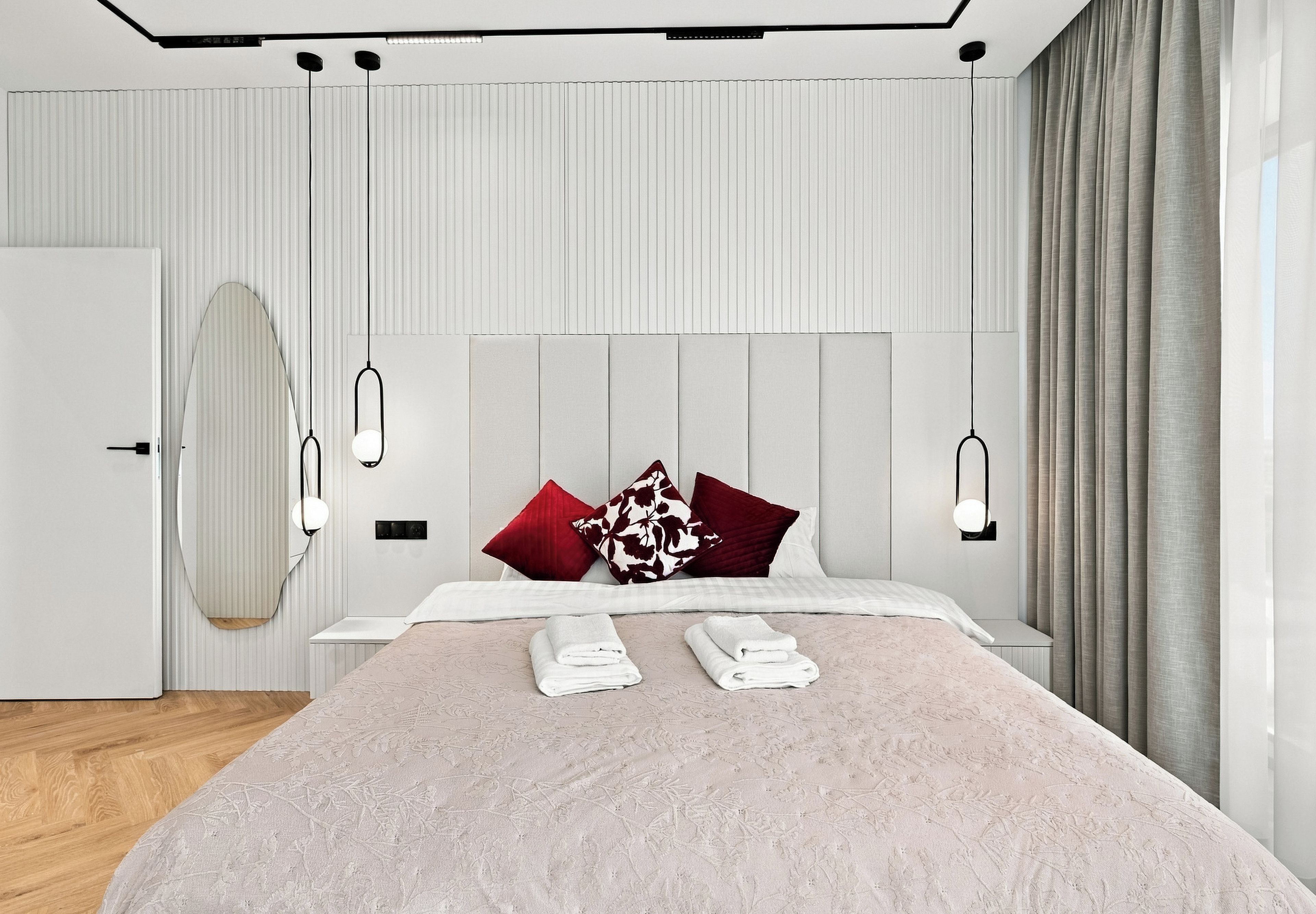 A modern bedroom with a bed, bedside tables, and a large window with curtains.