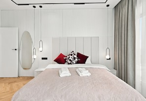 Un dormitorio moderno con cama, mesitas de noche y un amplio ventanal con cortinas.