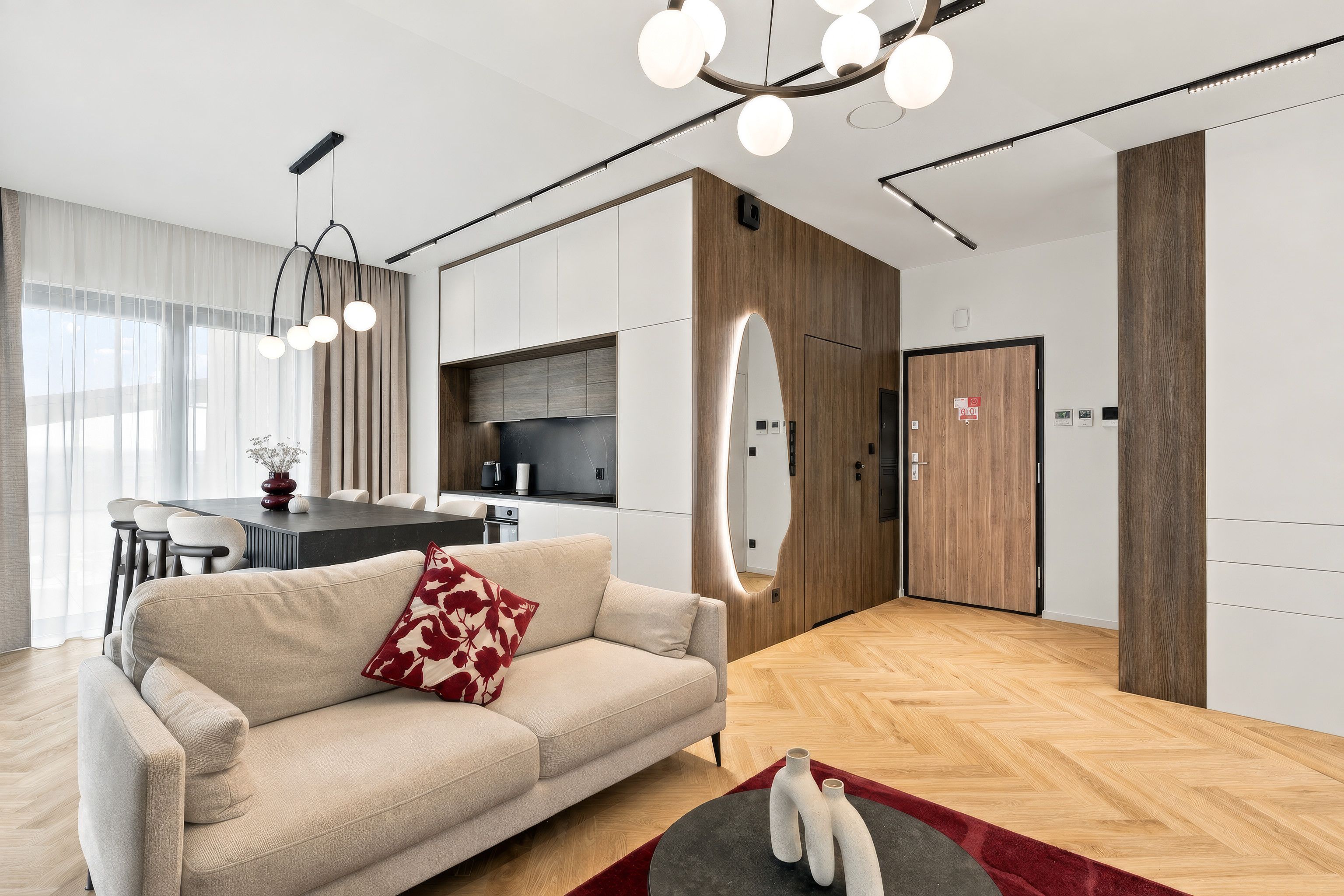 Ein modernes Wohnzimmer mit einer Couch, einem Essbereich mit Tisch und einer Küche im Hintergrund.