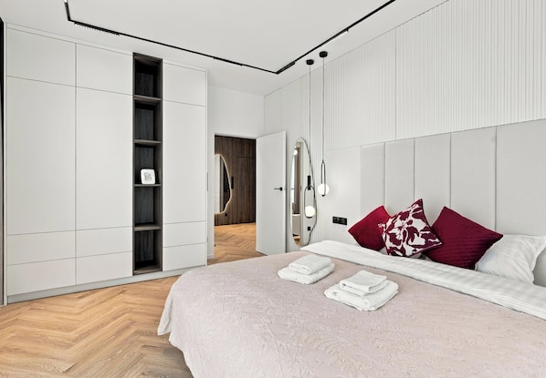 Quarto moderno com uma cama grande, guarda-roupa e toucador com espelhos.