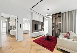Uma sala de estar moderna com televisão de tela plana, um tapete vermelho e um sofá.