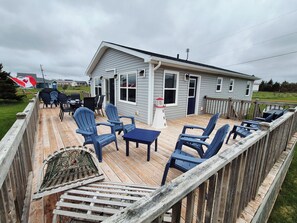 A deck with outdoor seating and a small building with windows. - North Shore Ocean View Beach House (Sea View)