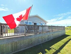 A house with a deck and a Canadian flag. - North Shore Ocean View Beach House (Sea View)