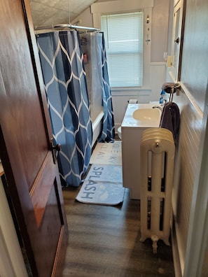 Ein kleines Badezimmer mit Duschvorhang, Waschbecken und Handtuchwärmer.
