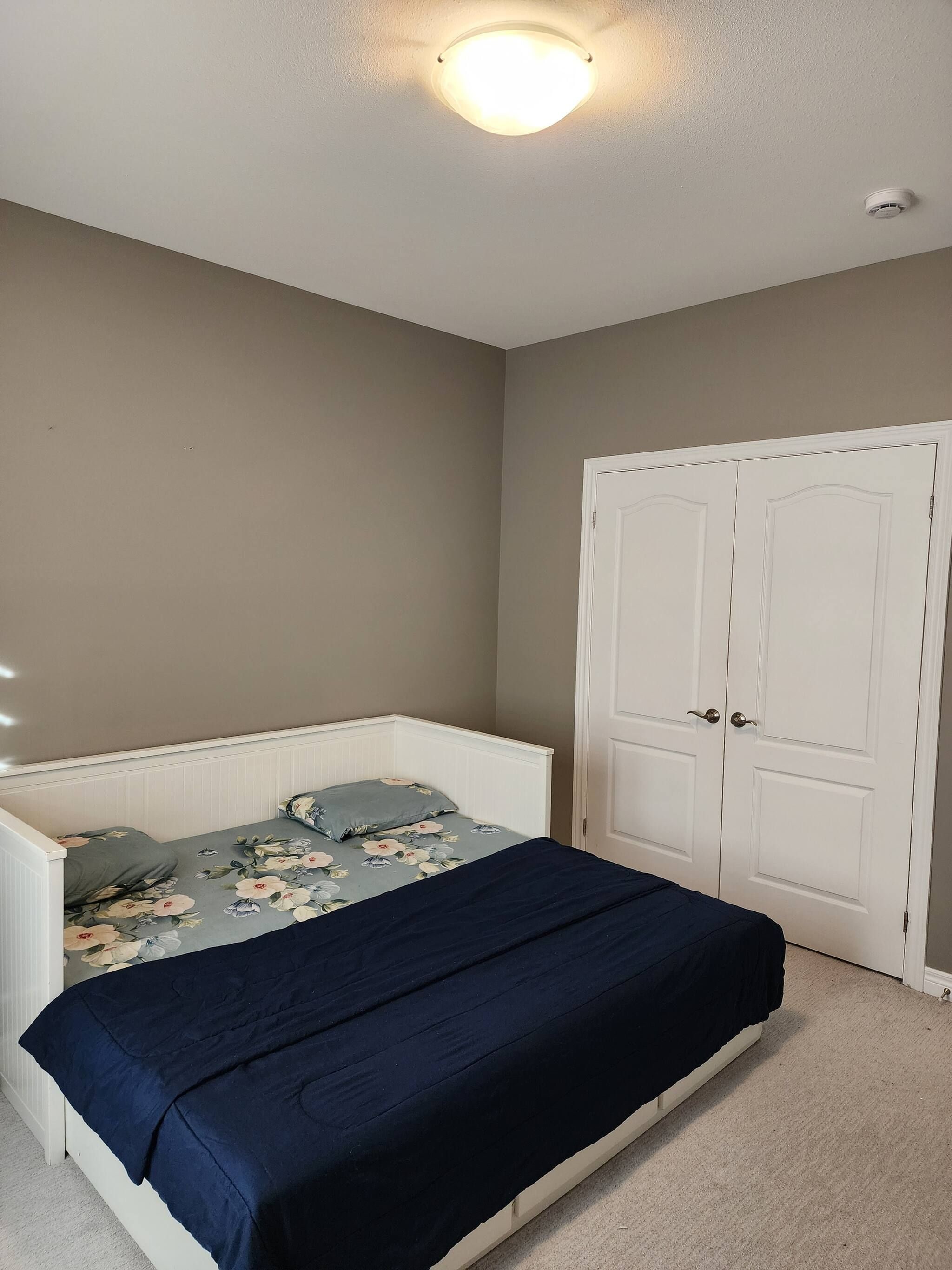 Ein Schlafzimmer mit einem Bett, einem weißen Kleiderschrank und einer Deckenleuchte.