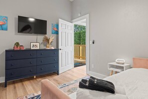A bedroom with a bed, a dresser, a television, and a door leading to a balcony. - Tampa Oasis - Private Heated Pool, Seminole Heights (Tampa)