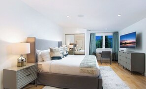 A modern bedroom with a large bed, bedside tables, a desk, and a television. - Crescent Terraza By Alora Reserve (Los Angeles)