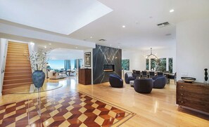 A spacious living area with a large wooden staircase, a checkered floor, and a modern fireplace. - Crescent Terraza By Alora Reserve (Los Angeles)