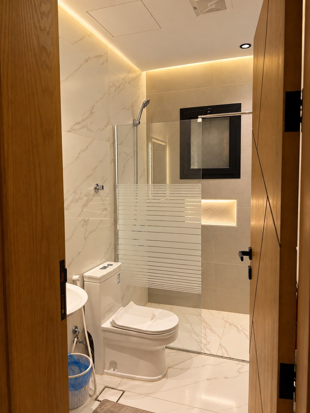 Un baño moderno con cabina de ducha de vidrio, inodoro y lavamanos.