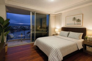 Ein Hotelzimmer mit einem großen Bett, einem Balkon mit Blick auf die Stadt und einem Bild an der Wand.