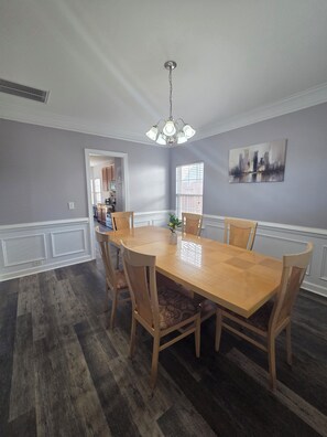 Ein Esszimmer mit Holztisch und -stühlen, einer Chandelier und einem Stadtbild an der Wand.