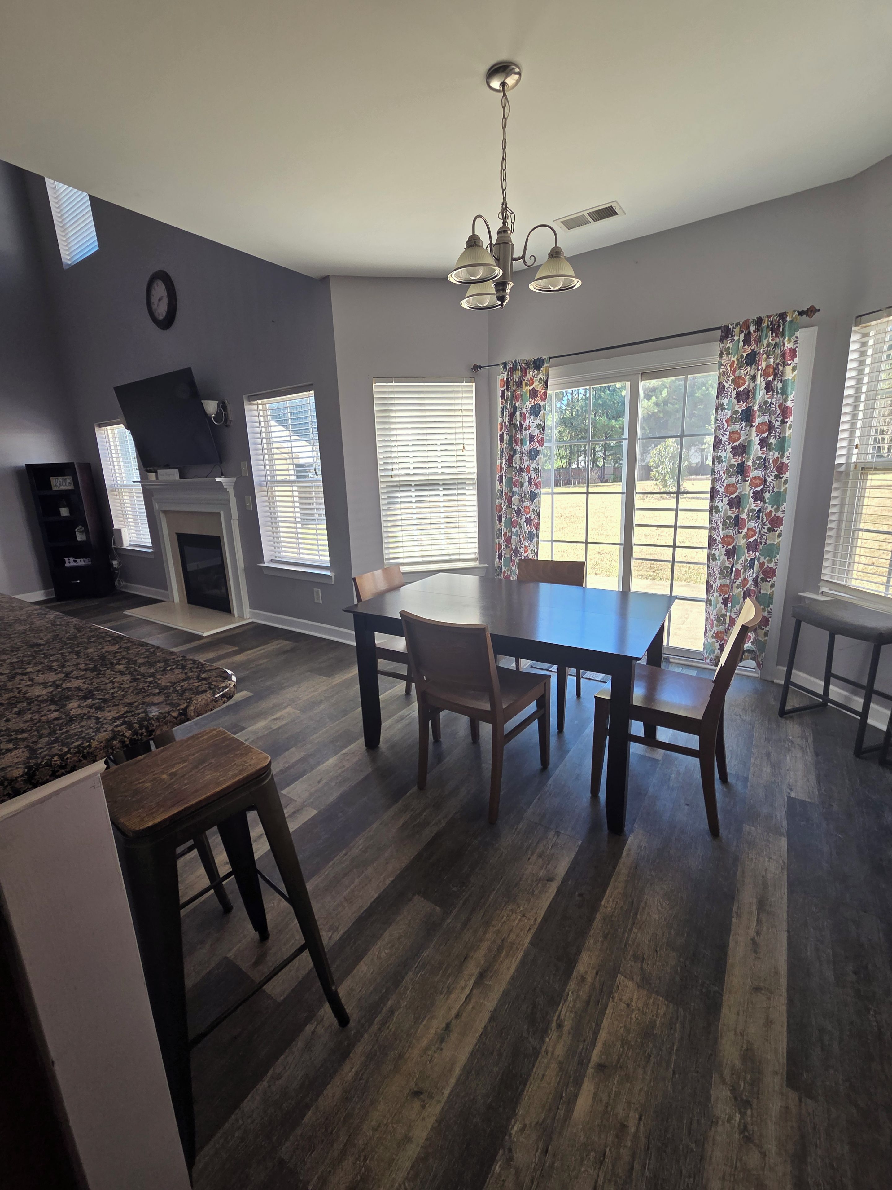 A dining area with a table and chairs, a fireplace, and a television on the wall.