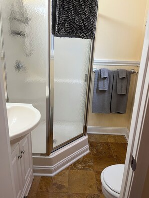 Une salle de bain avec une douche à parois de verre, un lavabo blanc et des toilettes.