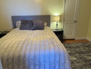 Un lit avec une tête de lit, une table de chevet avec une lampe et une porte.