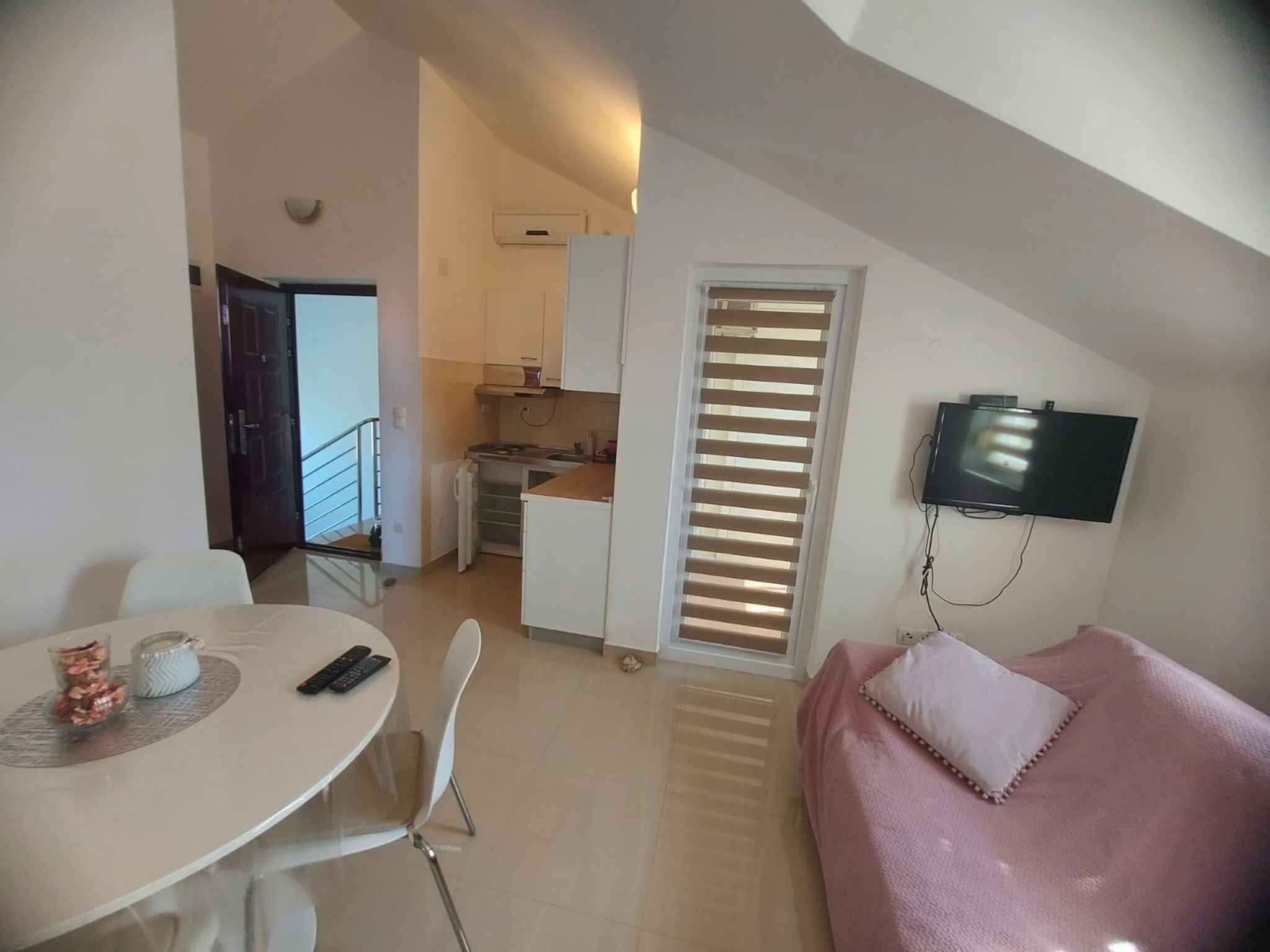 A modern living space with a dining area, kitchenette, and a TV mounted on the wall.